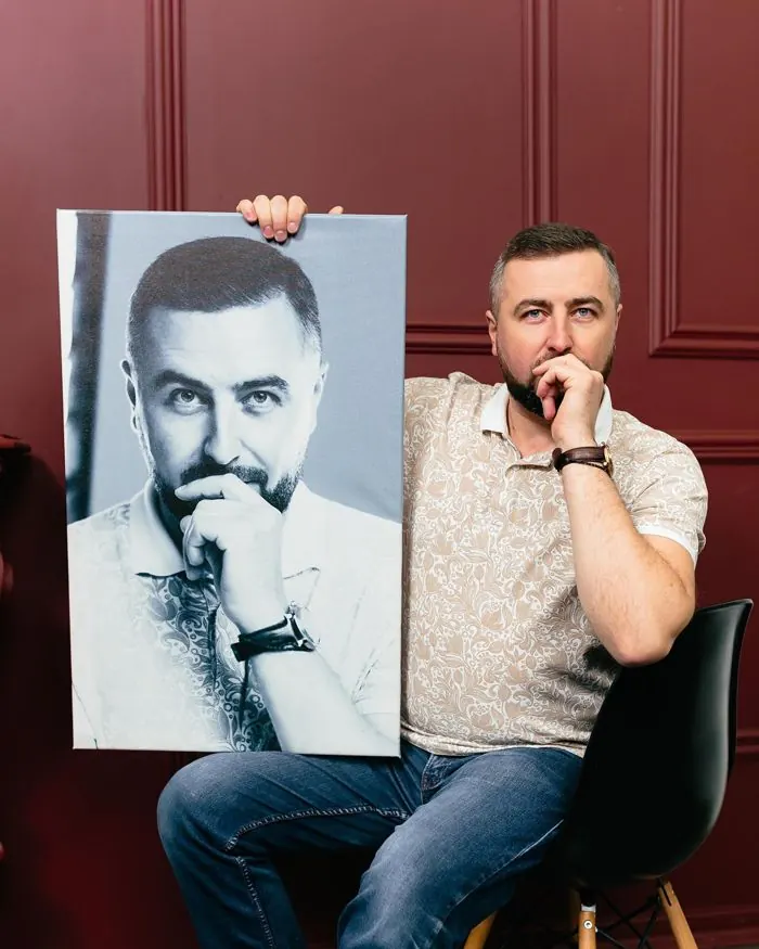 Чоловік тримає чорно-білий портрет на полотні